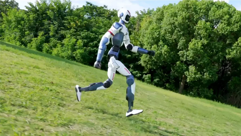 Robot humanoïde Unitree R1 courant sur une pente herbeuse