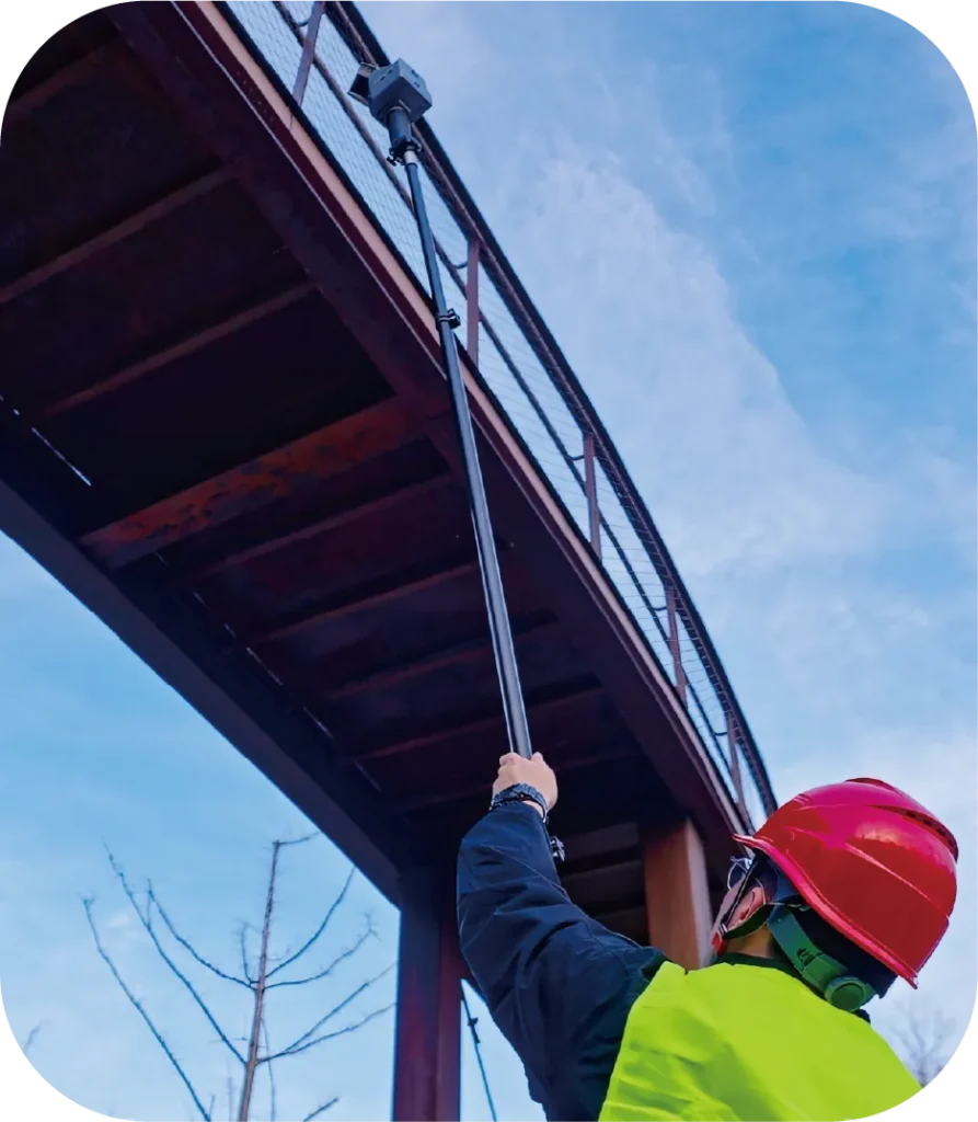 Opérateur scannant le dessous d'un pont avec le FJD Trion S2 sur perche télescopique