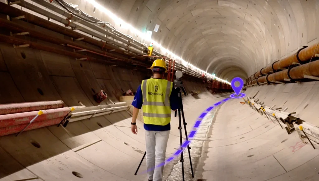 Opérateur déplaçant le FJD Trion T1 sur trépied entre deux stations dans un tunnel